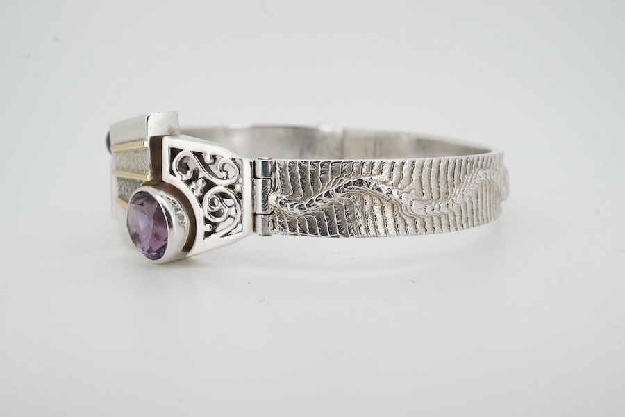 A contemporary silver and amethyst bangle, of abstract, Cubist-inspired design, to a textured band, set with a circular-cut amethyst and a cultured pearl, inner circumference approximately 20.8cm, maker's mark ZC, stampe